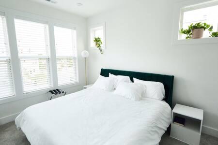 1 dormitorio con 1 cama blanca con sábanas blancas y ventanas en Hall House - Northeast Nashville Serene Rooftop Gem en Nashville