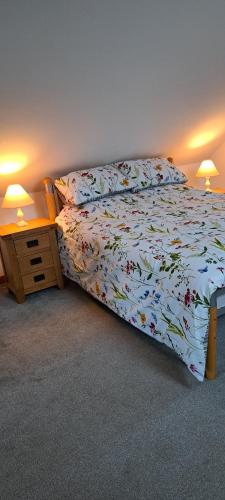 a bedroom with a bed and a night stand with two lamps at Robins Nest in Ingleton 