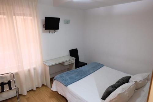 a bedroom with a bed and a desk and a television at Hostal Don Rodrigo in Zamora