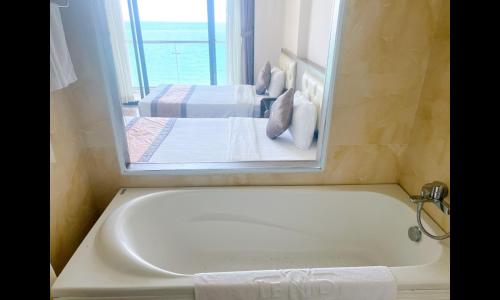 a bath tub in a room with two beds at Lenid Ocean View Hotel in Nha Trang