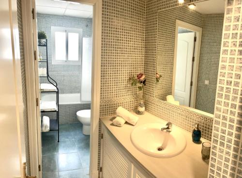 uma casa de banho com um lavatório, um WC e um espelho. em Apartamento Liru Bormujos 2, a 5 minutos de Sevilla em Bormujos