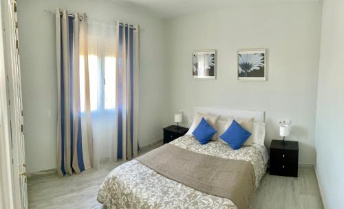 1 dormitorio con 1 cama con almohadas azules en Apartamento Liru Bormujos 2, a 5 minutos de Sevilla, en Bormujos