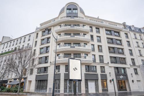 um edifício branco com um sinal em frente em Yuna Porte-Maillot - ApartHotel em Paris