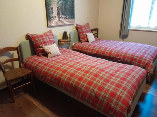 two beds in a room with a plaid blanket at La Mirabelle Gîte de charme in Mackenheim