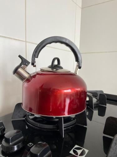 a red tea kettle sitting on top of a stove at AP Novo Mobiliado in Salvador