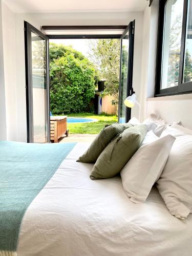 a bedroom with a white bed with a large window at Cascais Guincho Beach Villa in Cascais
