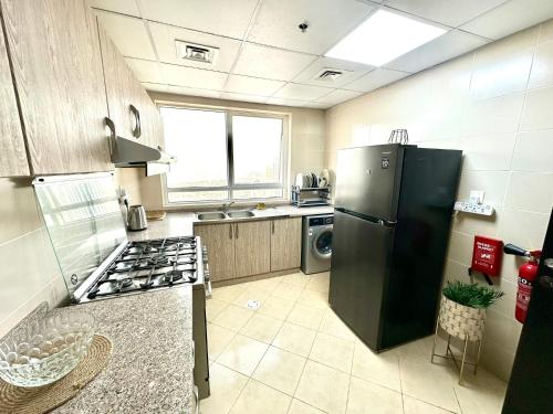 a kitchen with a black refrigerator and a stove at Luxury Appartement Amazing View 130m2 Al Majaz 3 in Sharjah