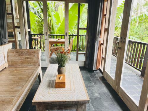 a porch with wooden benches and a vase with flowers at Widya Luxury House in Ubud