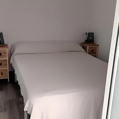 uma cama branca num quarto com duas mesas de cabeceira em Castelar em Rota