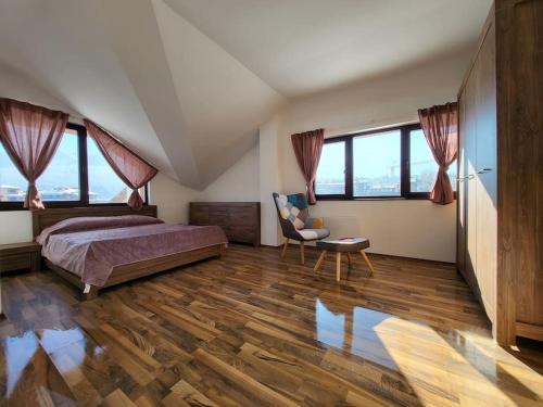 une chambre avec un lit, une chaise et des fenêtres dans l'établissement KS Rooftop 180°, à Bansko