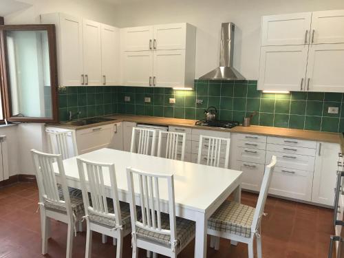 a kitchen with white cabinets and a white table and chairs at House near Rome with Beautiful Views and Pool in Piglio