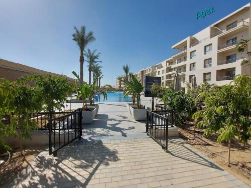 a walkway in front of a building with palm trees at Alumia Marigold Suite 3BR Apt Pool Access in Cairo
