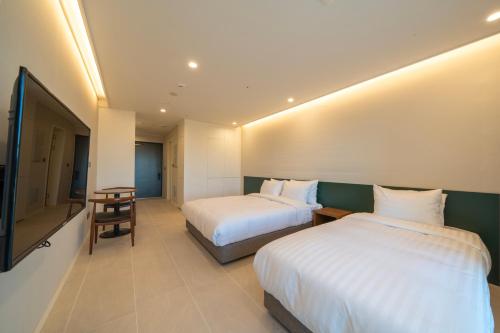 a hotel room with two beds and a television at Chestertons Naksan in Yangyang