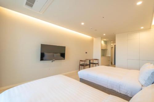a bedroom with two beds and a tv on the wall at Chestertons Naksan in Yangyang