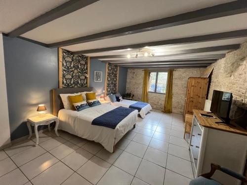 a bedroom with two beds and a flat screen tv at Les Bruyeres Chambres dhotes et Gite in Verteuil-sur-Charente