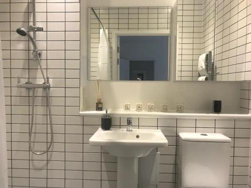 a bathroom with a sink and a toilet and a mirror at Central Charm Dwelling in London