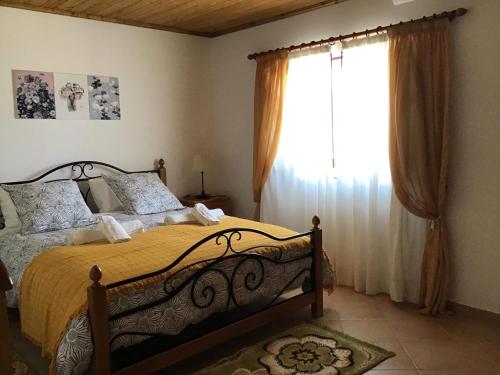 a bedroom with a bed and a large window at Monte da Palmeirinha in Vila Nova de Milfontes