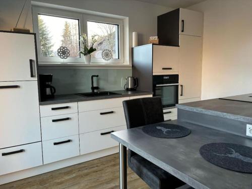 a kitchen with white cabinets and a table in it at Ferienhaus H-Auszeit in Fichtelberg