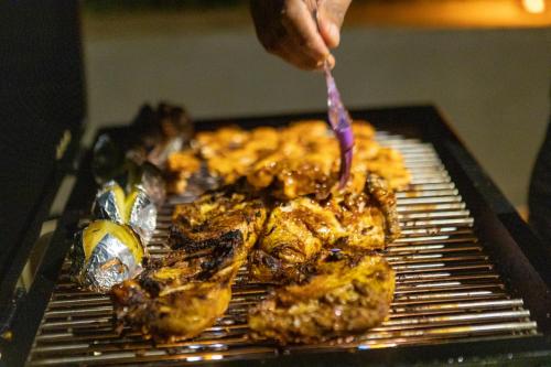 a person is cooking food on a grill at Amore Resorts in Kobbekaduwa
