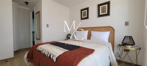 een witte slaapkamer met een bed en een bord aan de muur bij MC Suite 1 Norte in Antofagasta