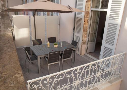 - une table avec des chaises et un parasol sur le balcon dans l'établissement Le charmant cocon, à La Bourboule