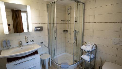 ein Bad mit einer Dusche und einem Waschbecken in der Unterkunft Ferienwohnungen Hotel Eden Spiez in Spiez