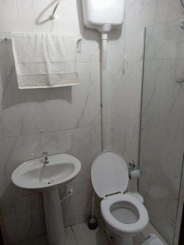 La salle de bains blanche est pourvue de toilettes et d'un lavabo. dans l'établissement Flor da serra, à Santo Antônio do Pinhal