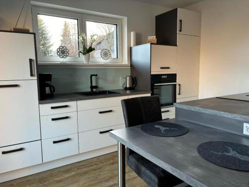 a kitchen with white cabinets and a table with chairs at Ferienhaus H-Auszeit in Fichtelberg