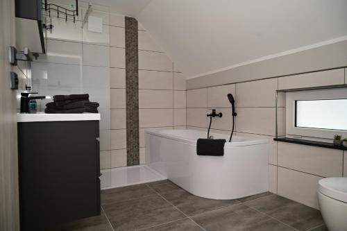 a bathroom with a tub and a toilet and a television at Ferienwohnung am Kalten Bach in Dürrröhrsdorf