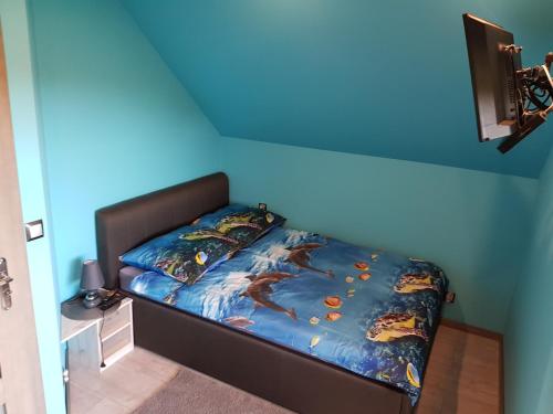 a bed in a room with a blue wall at Revela Domki Całoroczne Boszkowo in Boszkowo