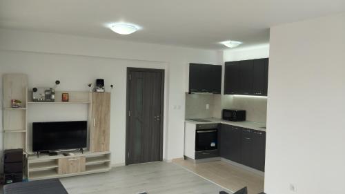 a kitchen with black cabinets and a flat screen tv at Valemar Apartments in Pomorie