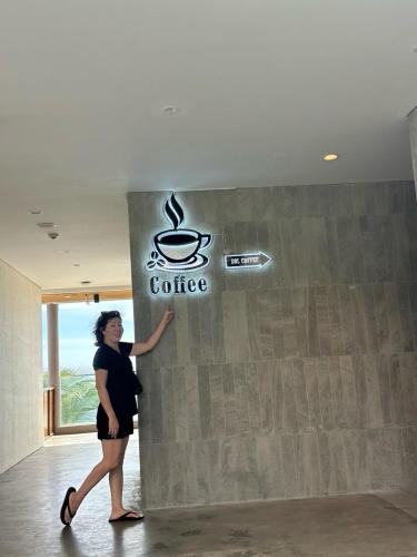 a woman standing next to a wall with a coffee sign at Mandala Muine M2012A in Phan Thiet