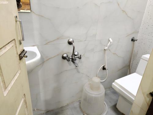 a white bathroom with a toilet and a sink at Nile Guest House in Chennai