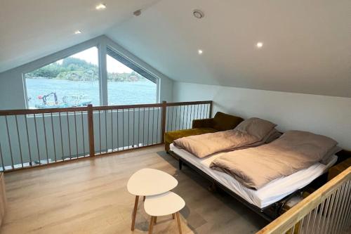 1 dormitorio con cama, mesa y balcón en Eksklusiv Rorbu - Havblikk 1 - Båtutleie en Bekkjarvik