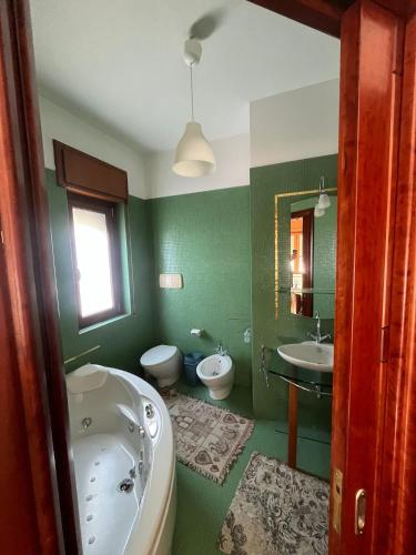 ein grünes Bad mit einer Badewanne und einem Waschbecken in der Unterkunft CASA ZANON in Quattromiglio