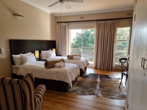 een slaapkamer met 2 bedden en een groot raam bij The Green Lizard Guesthouse in Nelspruit