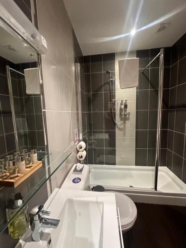a bathroom with a sink and a shower and a toilet at The Bell Guesthouse in Peterlee