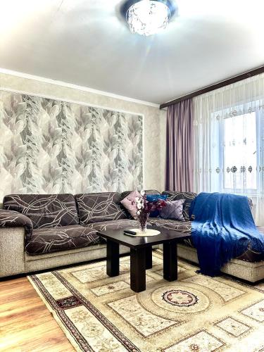 a living room with a couch and a table at Двухкомнатная квартира в центре in Semey
