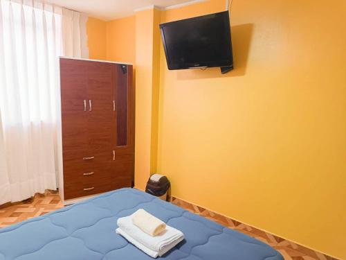 A y J Familia Hospedaje في ليما: غرفة نوم مع سرير وتلفزيون على الحائط