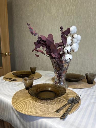 una mesa con un jarrón de flores sobre una mesa en Двухкомнатная квартира в центре, en Semey