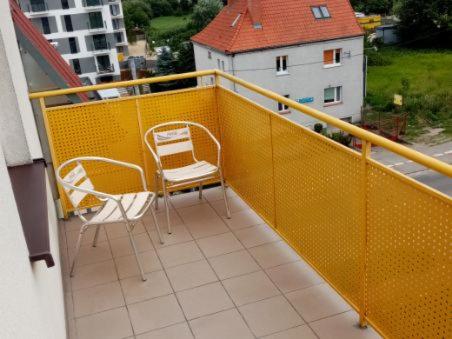 a balcony with two chairs and a yellow railing at Apartment Inter Trade fair Poznan in Poznań