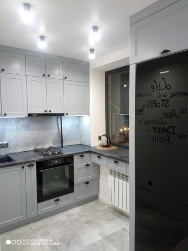 a kitchen with white cabinets and a black refrigerator at Lovely apartment in Tiraspol