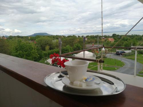 a cup of coffee on a plate on a balcony at Jurta Hotel Balatongyörök in Balatongyörök