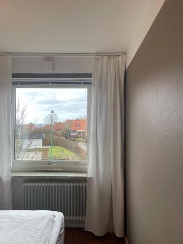 a bedroom with a window with a white curtain at Hemmet B&B in Simrishamn