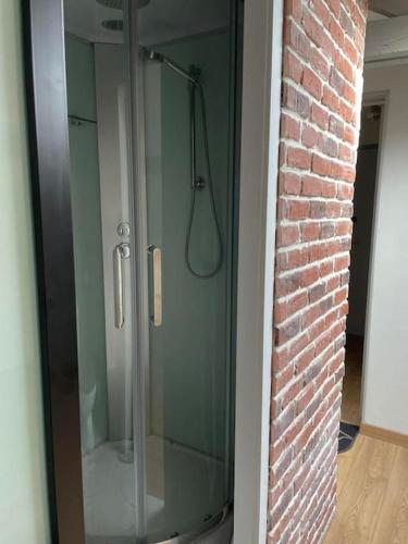 - une cabine de douche en verre dans une chambre dotée d'un mur en briques dans l'établissement Edouard 2. logement complet., à Charleville-Mézières