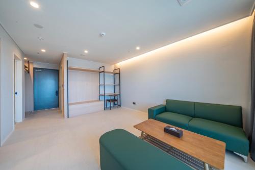 a living room with a green couch and a table at Chestertons Naksan in Yangyang