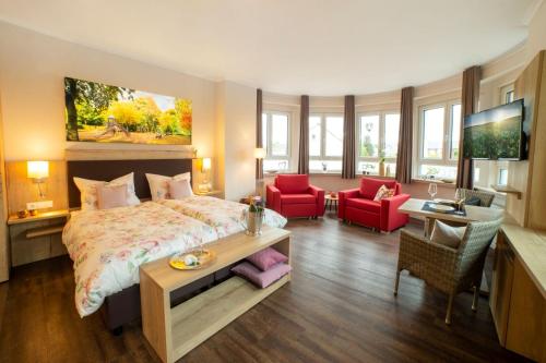 una camera con un letto e due sedie rosse di Hotel Velo a Quakenbrück