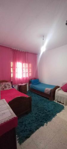 two beds in a room with pink and blue at Le Kram House in La Goulette