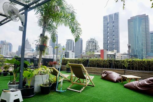 a patio with chairs and plants and a city skyline at Hip and funky apartment silom Soi 3, with rooftop view in Bangkok