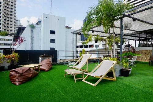 a patio with chairs and grass on a roof at Hip and funky apartment silom Soi 3, with rooftop view in Bangkok